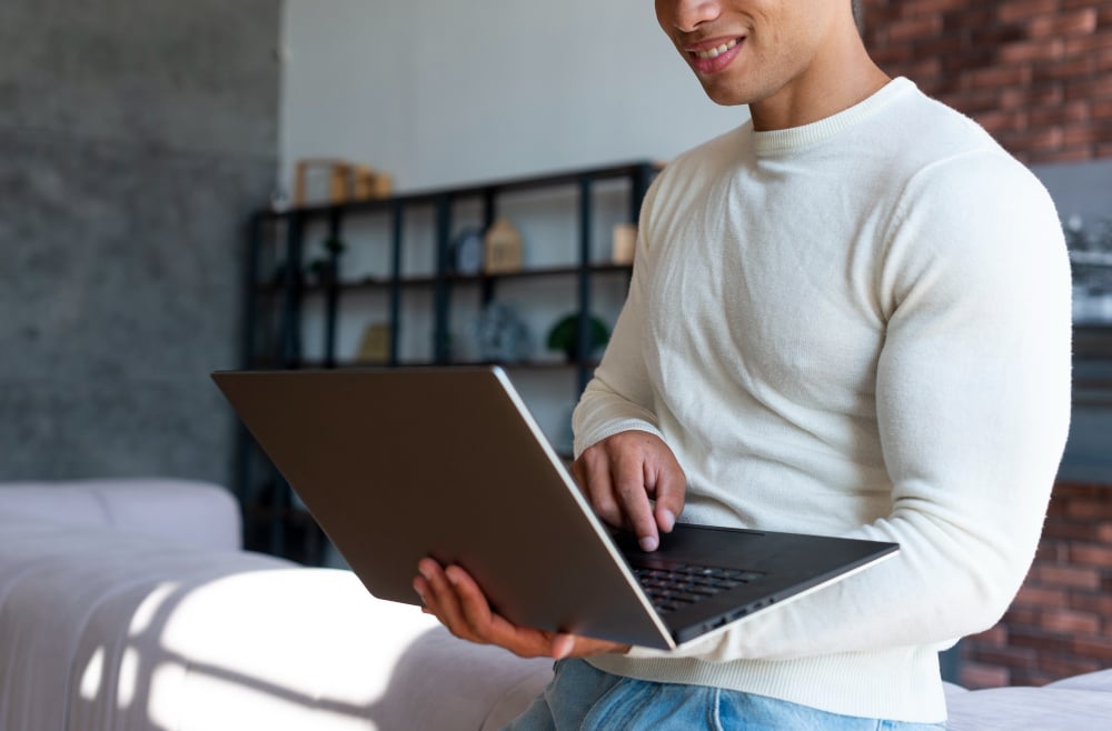 man smiling and using a laptop - Speechify Alternatives
