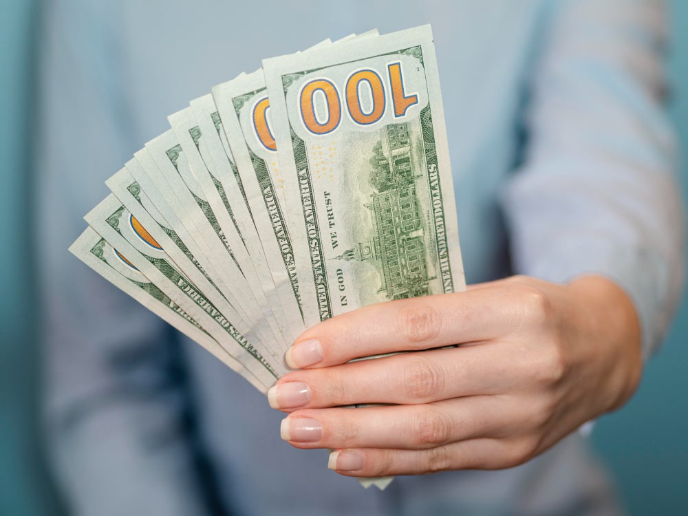 man holding dollar bills - How Much Does Speechify Cost