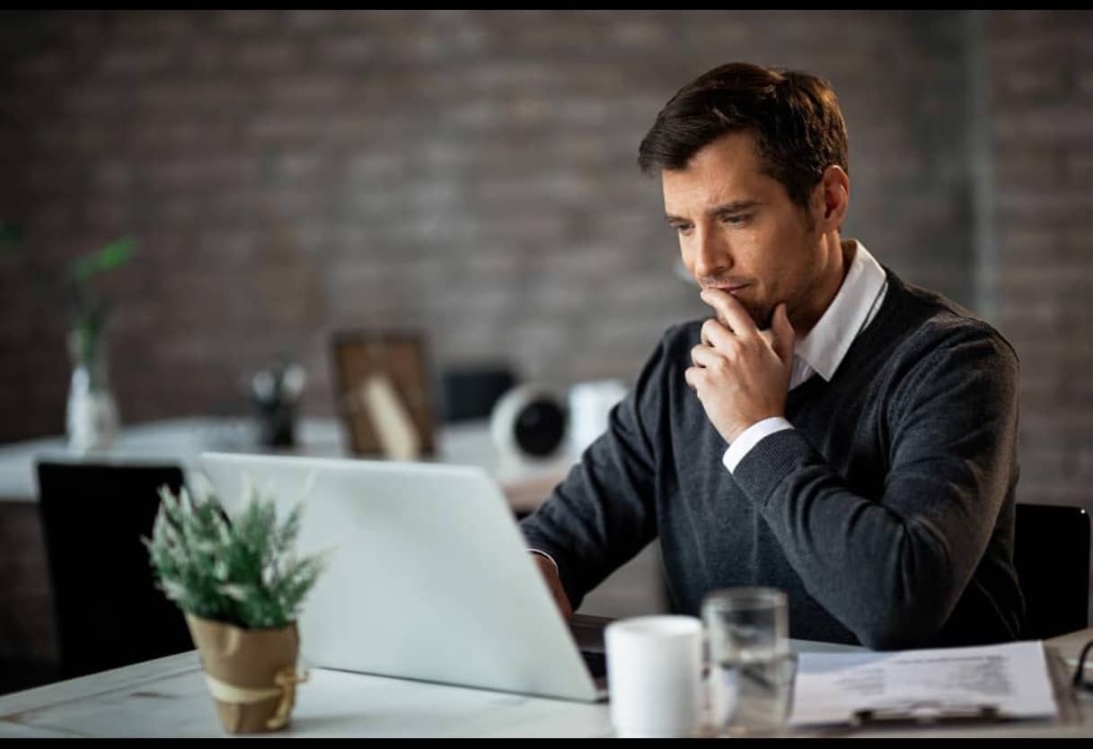 man thinking and using a laptop - How Much Does Speechify Cost