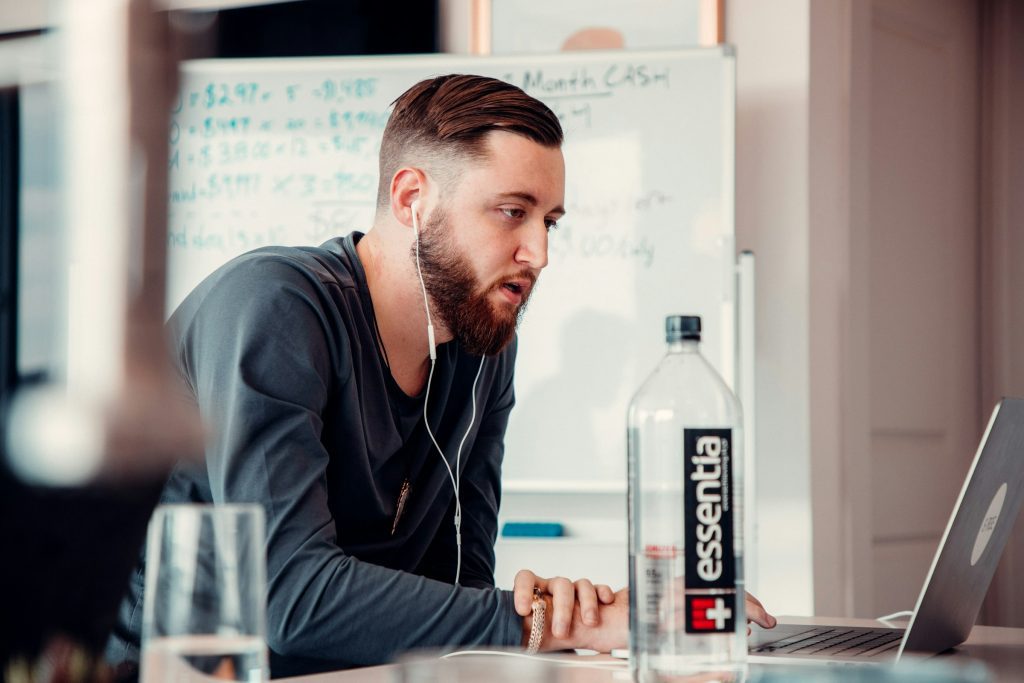 man wearing headphones and using a laptop - Speechify Alternatives