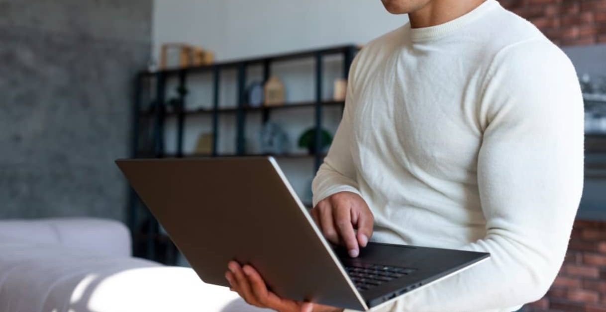 man smiling and using a laptop - Speechify Alternatives