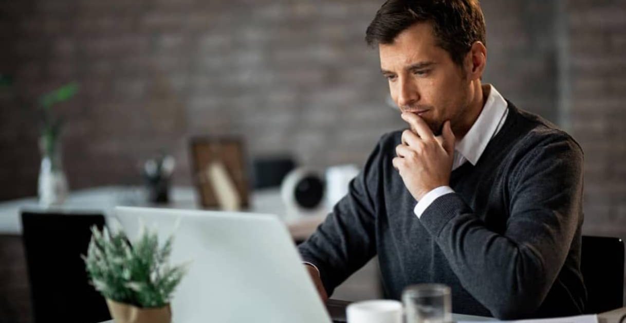 man thinking and using a laptop - How Much Does Speechify Cost